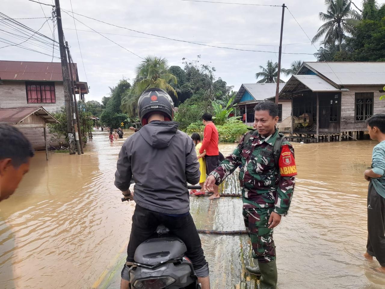 Babinsa bersama Relawan Bantu Warga Menyebrangi Banjir Dengan Rakit Bambu
