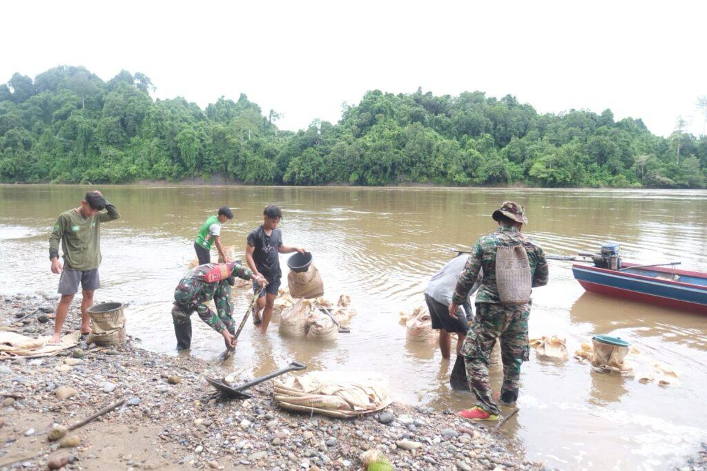 Bersama Warga Anggota Satgas TMMD Manfaatkan Batu Dari Sungai Mahakam Untuk Semenisasi Jalan